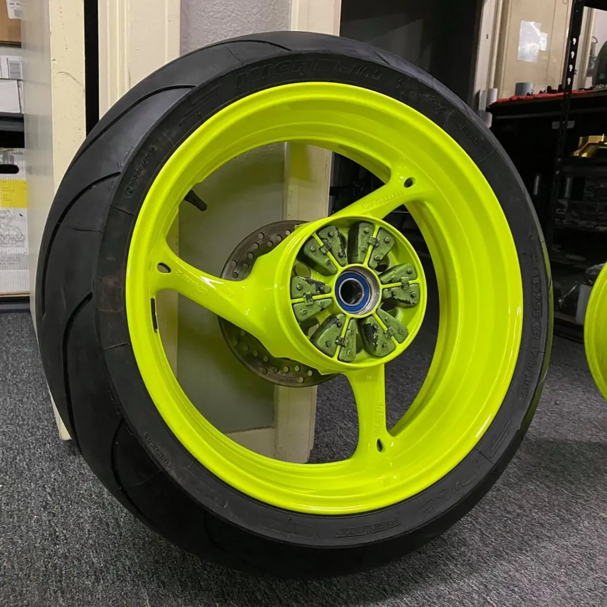 Sport bike wheel refinished in a 3-stage fluorescent yellow. Tires and bearings serviced in house