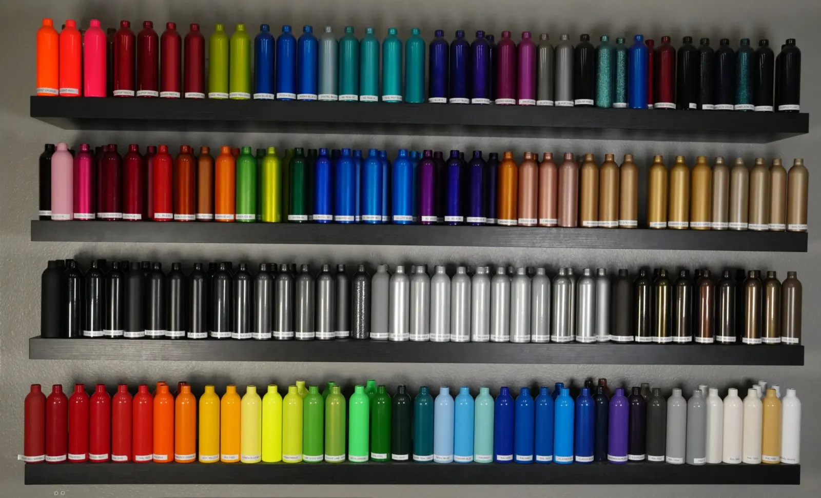 The color wall at Unit F14: four shelves of powder-coated sample bottles, about 100 colors, each labeled.
